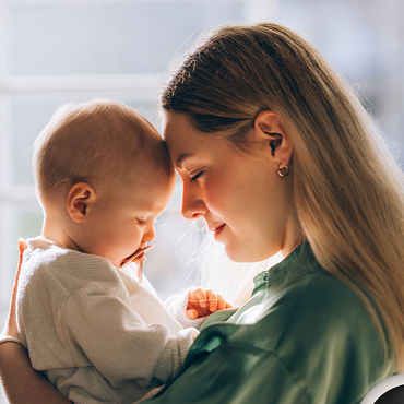 Mamma e bambino si sfiorano delicatamente la fronte e si godono un momento di intimità.