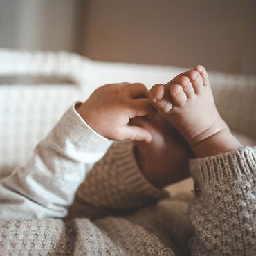 Baby hands playing with little baby feet, close-up with warm colours.