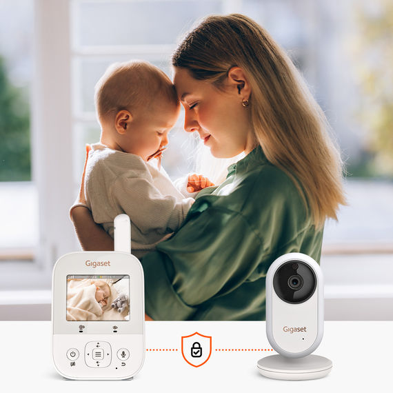 Madre che tiene amorevolmente in braccio il suo bambino, il video baby monitor Gigaset BABY 300 mostra il bambino che dorme sul display.