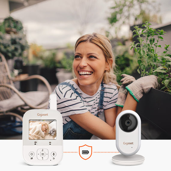 Une femme profite du jardinage sur la terrasse tandis que le babyphone vidéo Gigaset BABY 300 permet de surveiller son bébé.