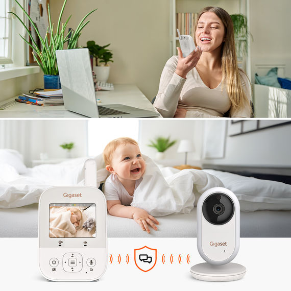 Mutter spricht ins Babyphone-Mikrofon, Baby liegt lachend im Bett; Gigaset BABY 300 Video mit Zwei-Wege-Kommunikation.