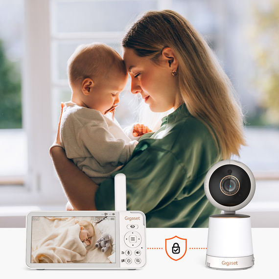 Madre che tiene amorevolmente in braccio il suo bambino, il video baby monitor Gigaset BABY 500 mostra il bambino che dorme sul display.