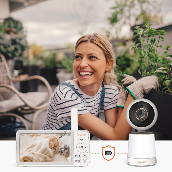 Une femme profite du jardinage sur la terrasse tandis que le babyphone vidéo Gigaset BABY 300 permet de surveiller son bébé.