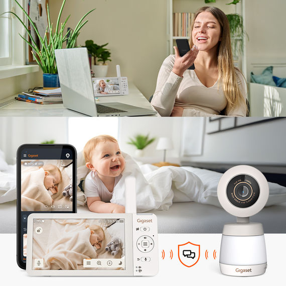 Donna che utilizza la comunicazione bidirezionale tramite app per smartphone, bambino sorridente nel letto; telecamera Gigaset BABY 700 Connected in primo piano.