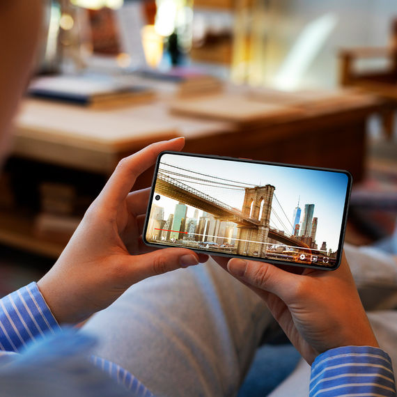 Persoon bekijkt video op Gigaset GS6 met stadsgezicht op scherm
