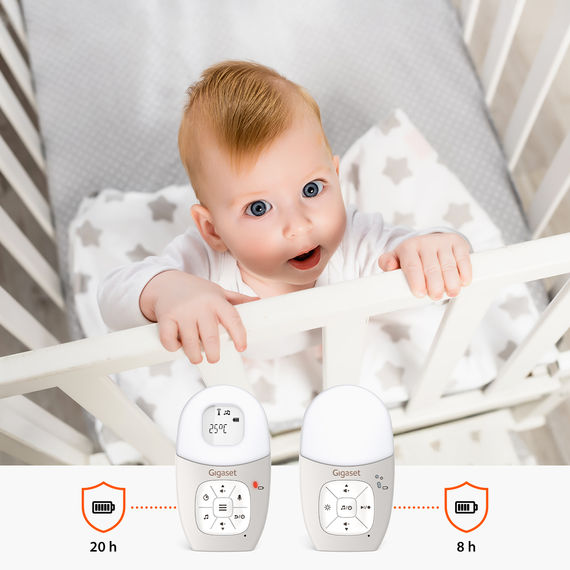 Baby monitor con unità genitore e bambino. Sullo sfondo, un bambino nella sua culla.