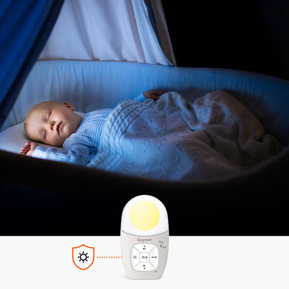 Babyphone au premier plan. À l'arrière-plan, un bébé endormi dans son berceau.