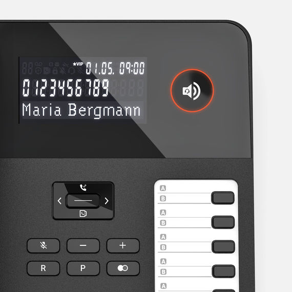 Primer plano de un teléfono de sobremesa con pantalla y teclas de función, aparece el nombre 