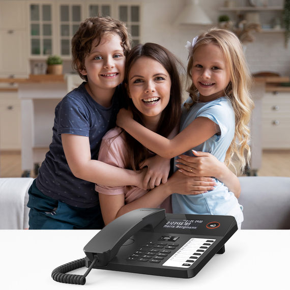Moderne bureautelefoon met display en functietoetsen, op de achtergrond een moeder en twee kinderen.